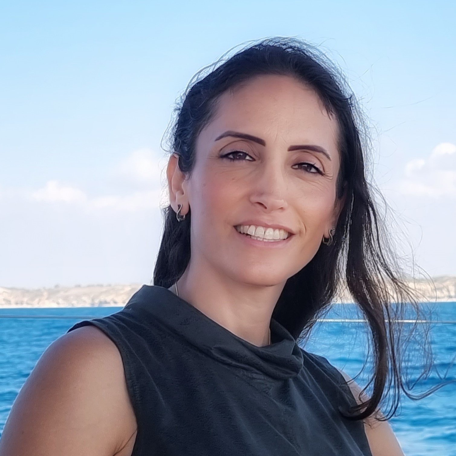 ליאת יהודה מחייכת, מבט חם ורגוע — תמונה של מדריכה שמלווה אימהות בדרך לשקט ואנרגיה בבית